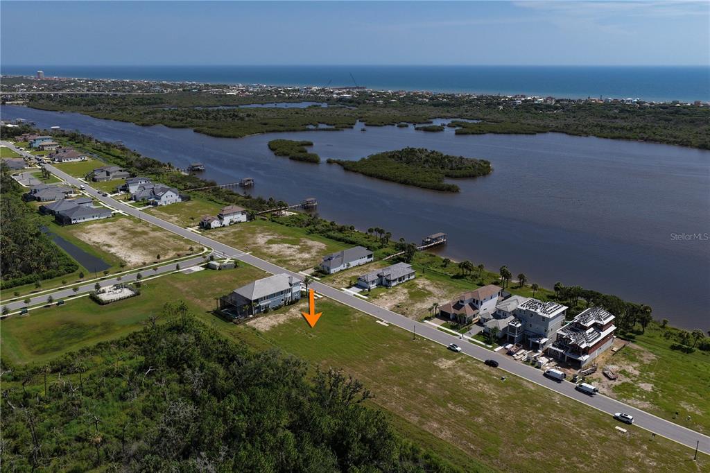 An aerial view shows a vacant residential lot situated between houses near a large waterway — 89 CORONADO ROAD, FLAGLER BEACH, FL