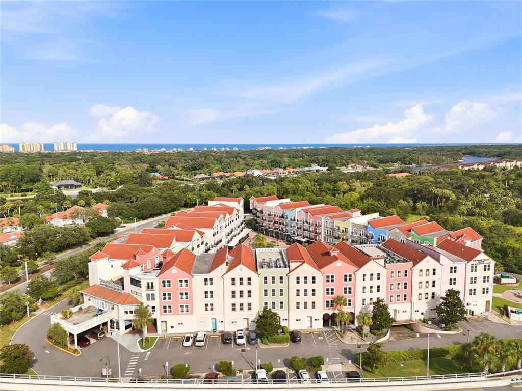 A multi-tiered stone fountain sits in a courtyard between two multi-story buildings connected by bridges — 101 PALM HARBOR PKWY UNIT B418, PALM COAST, FL