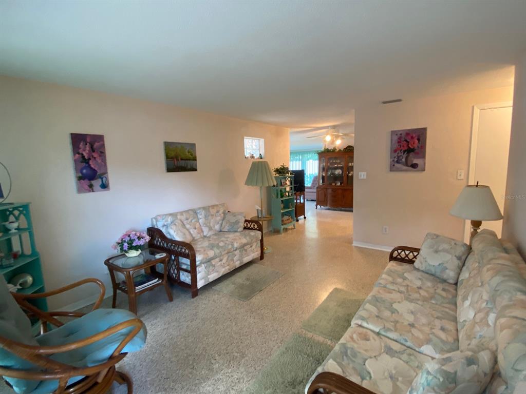 A living room features floral sofas, a rattan chair, and a wooden hutch in the background — 814 E 10th AVENUE, NEW SMYRNA BEACH, FL
