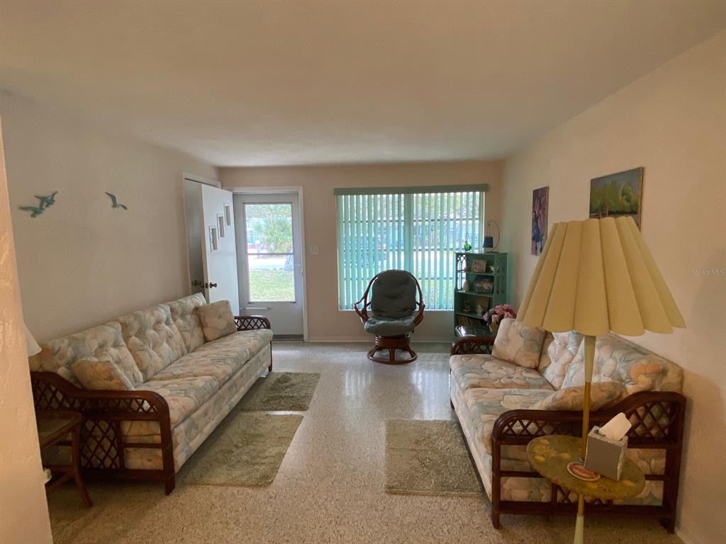 A living room features two floral sofas, a central rocking chair, and a floor lamp — 814 E 10th AVENUE, NEW SMYRNA BEACH, FL