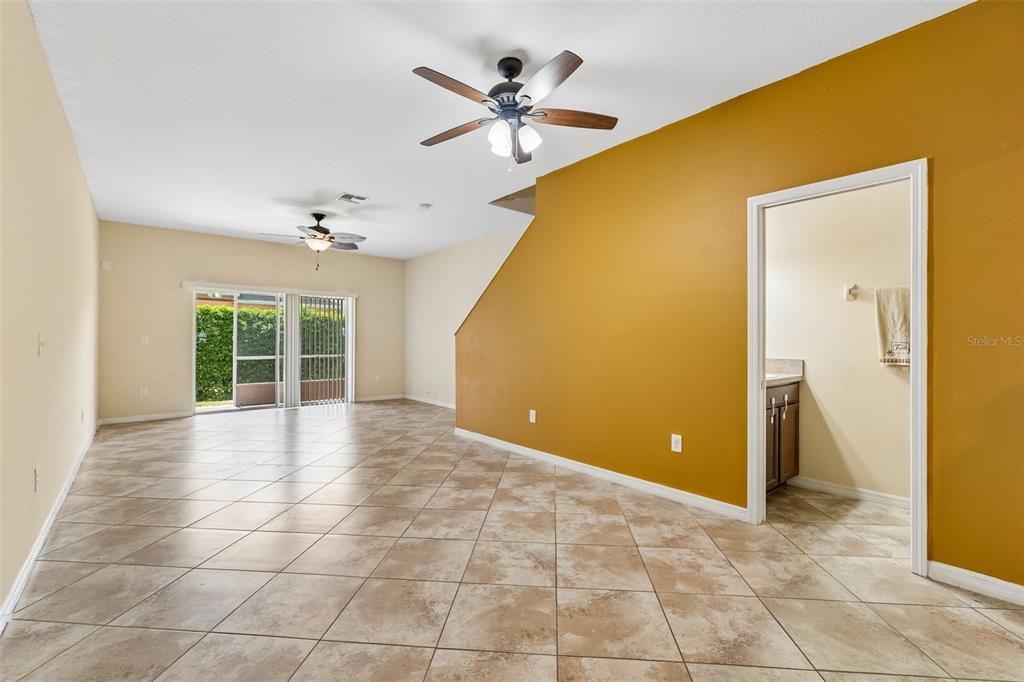 An open living area features tan tile flooring, mustard-colored walls, and sliding glass patio doors — 4127 SHADE TREE LANE, LAKELAND, FL