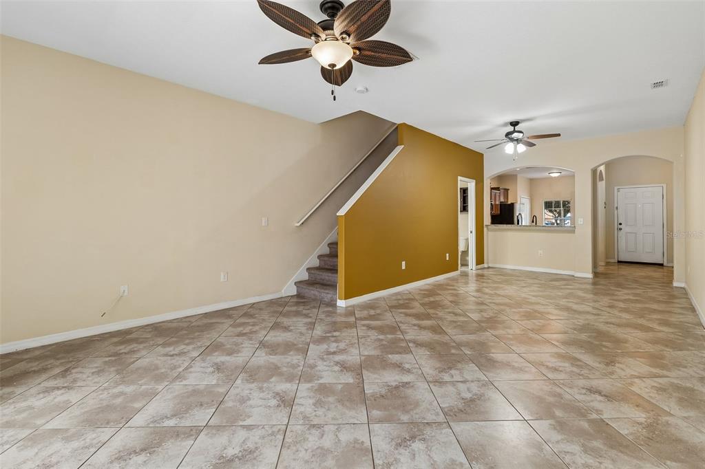 An open living area features tile flooring, a staircase, and a mustard-colored accent wall — 4127 SHADE TREE LANE, LAKELAND, FL