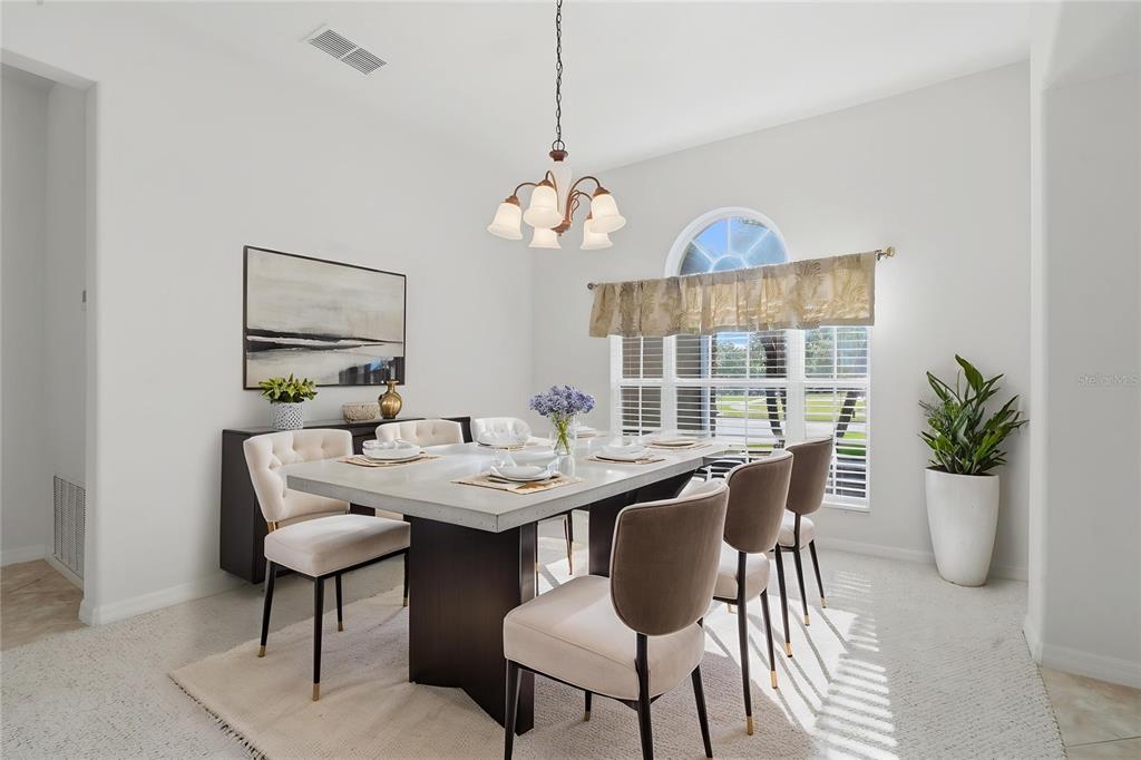 A dining room features a concrete-top table, upholstered chairs, a chandelier, and a large window — 4203 ROCK HILL LOOP, APOPKA, FL