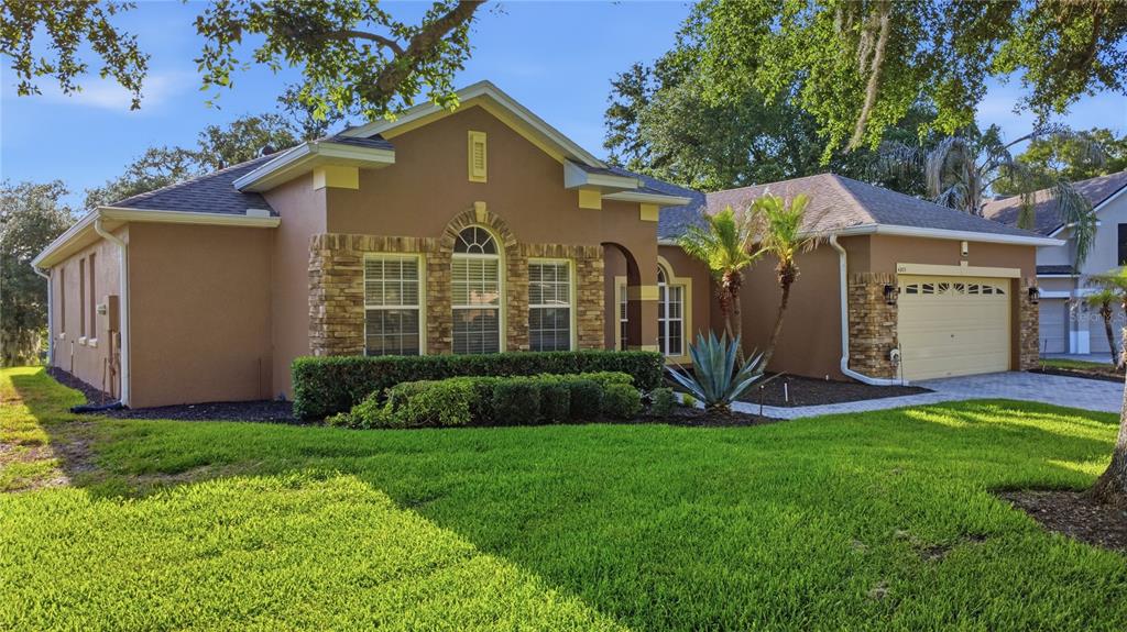 A single-story house with tan stucco walls, stone accents, and a two-car garage — 4203 ROCK HILL LOOP, APOPKA, FL