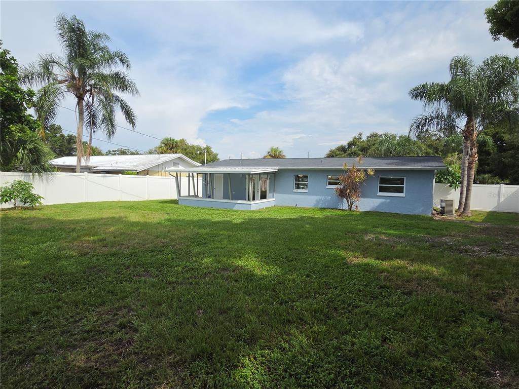 A view of a lake bordered by green grass and houses in the distance — 10827 VILLAGE GREEN AVENUE, SEMINOLE, FL