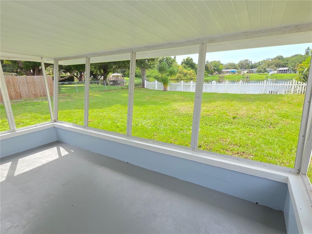 A view of a calm lake with grassy banks and houses in the background — 10827 VILLAGE GREEN AVENUE, SEMINOLE, FL