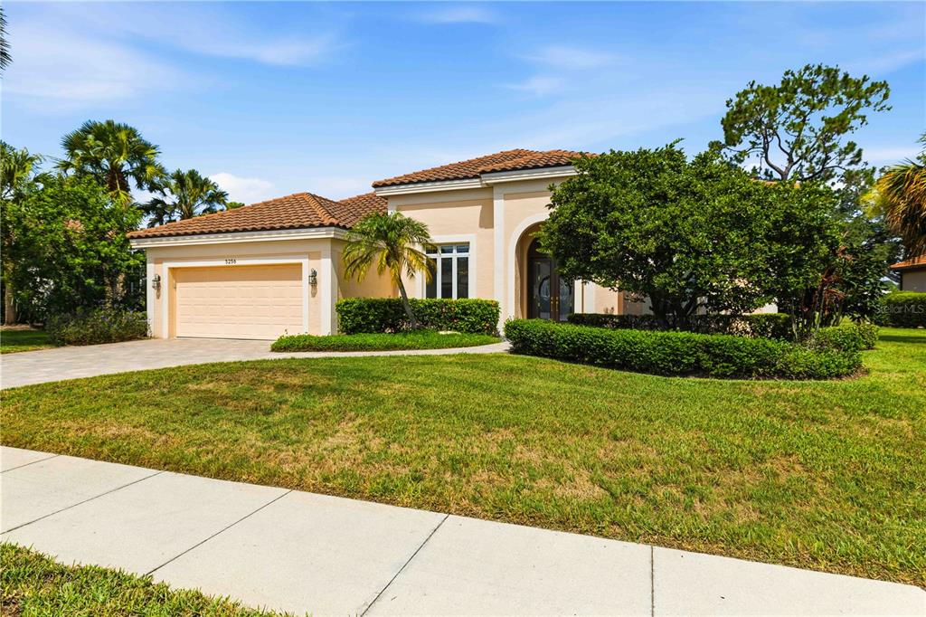 A single-story house with a beige stucco exterior, a tile roof, and a paved driveway — 5256 E 88TH STREET, BRADENTON, FL