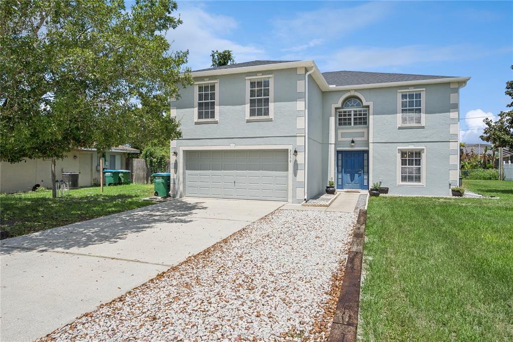 A two-story house with a light blue exterior, a garage, and a gravel driveway — 2330 DOVER STREET, DELTONA, FL