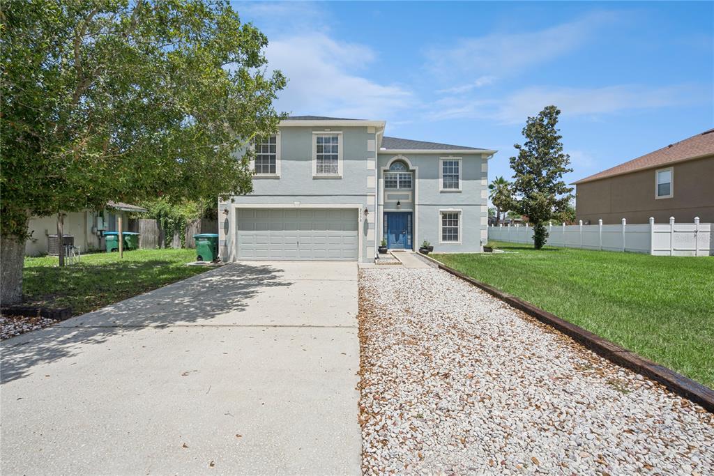 A two-story house with a light blue exterior, a concrete driveway, and a gravel path — 2330 DOVER STREET, DELTONA, FL