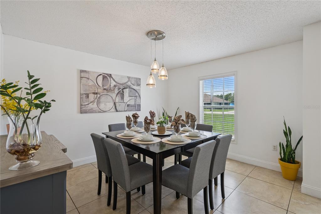 A dining room features a dark wood table, six gray chairs, and a pendant light — 2330 DOVER STREET, DELTONA, FL