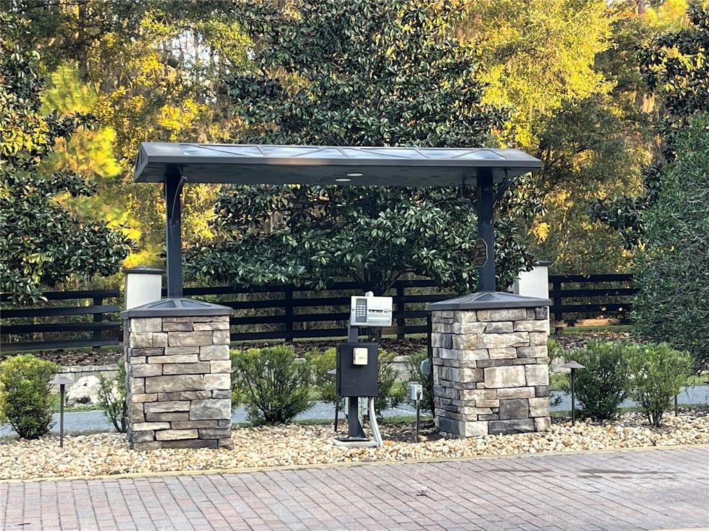 A stone-pillared gated entrance features a metal roof structure and a central intercom system — NW 145TH AVE LOT 25, WILLISTON, FL