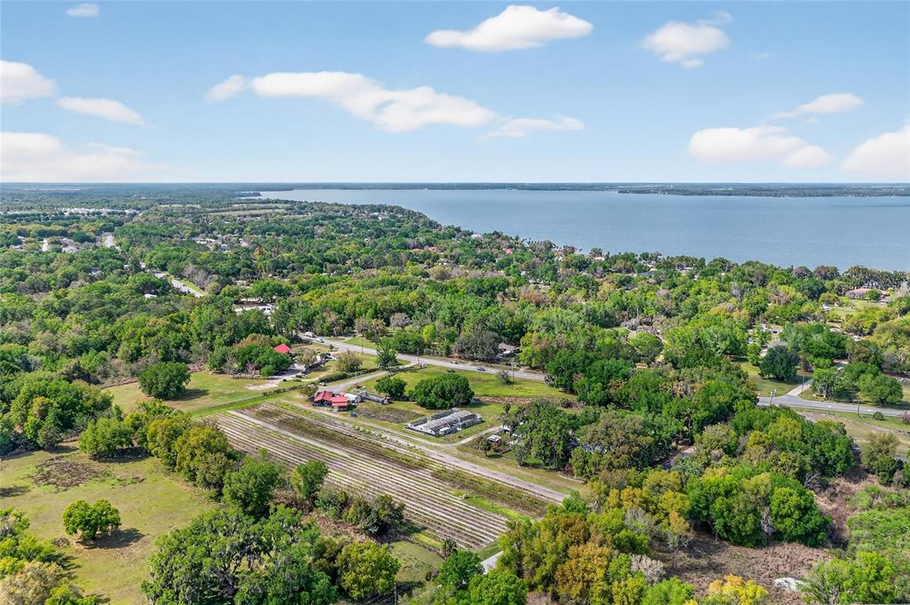 An aerial view shows a rural landscape with a large lake, trees, and agricultural fields — CR 48, YALAHA, FL