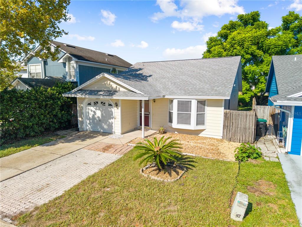 A single-story house with light yellow siding, a gray shingled roof, and a front driveway — 1094 MARTIN BOULEVARD, ORLANDO, FL