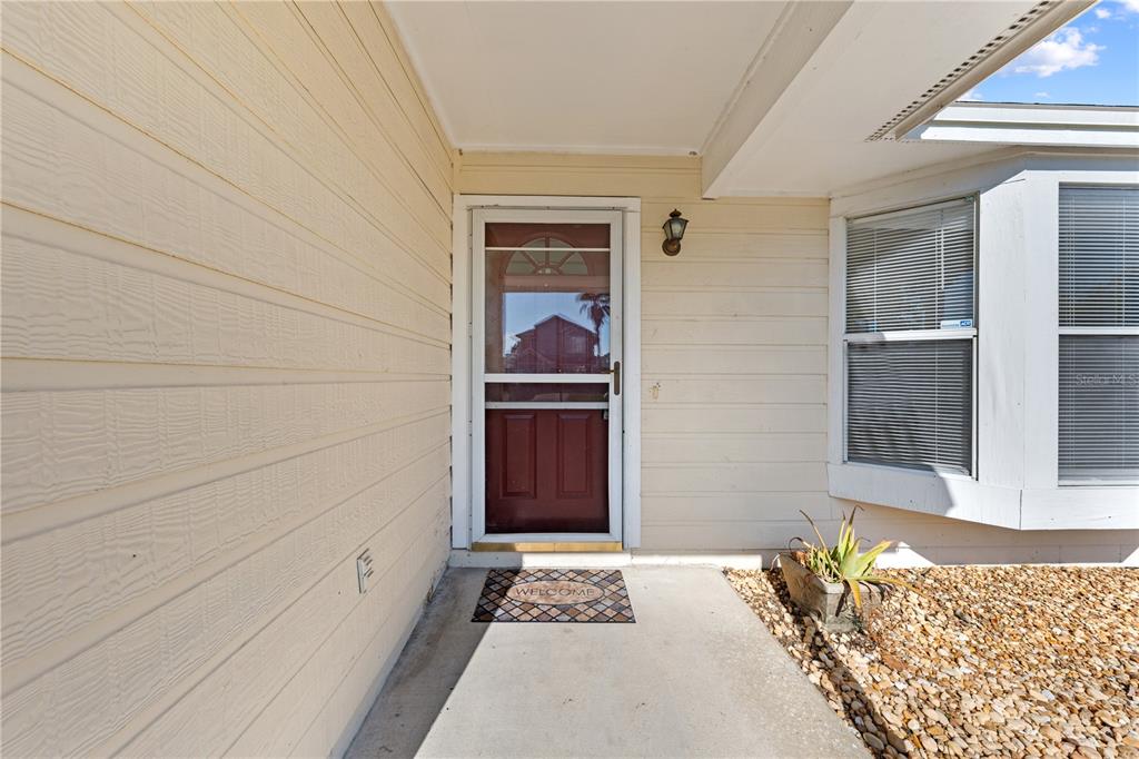 The exterior view shows a beige house entrance with a storm door and a gravel bed — 1094 MARTIN BOULEVARD, ORLANDO, FL