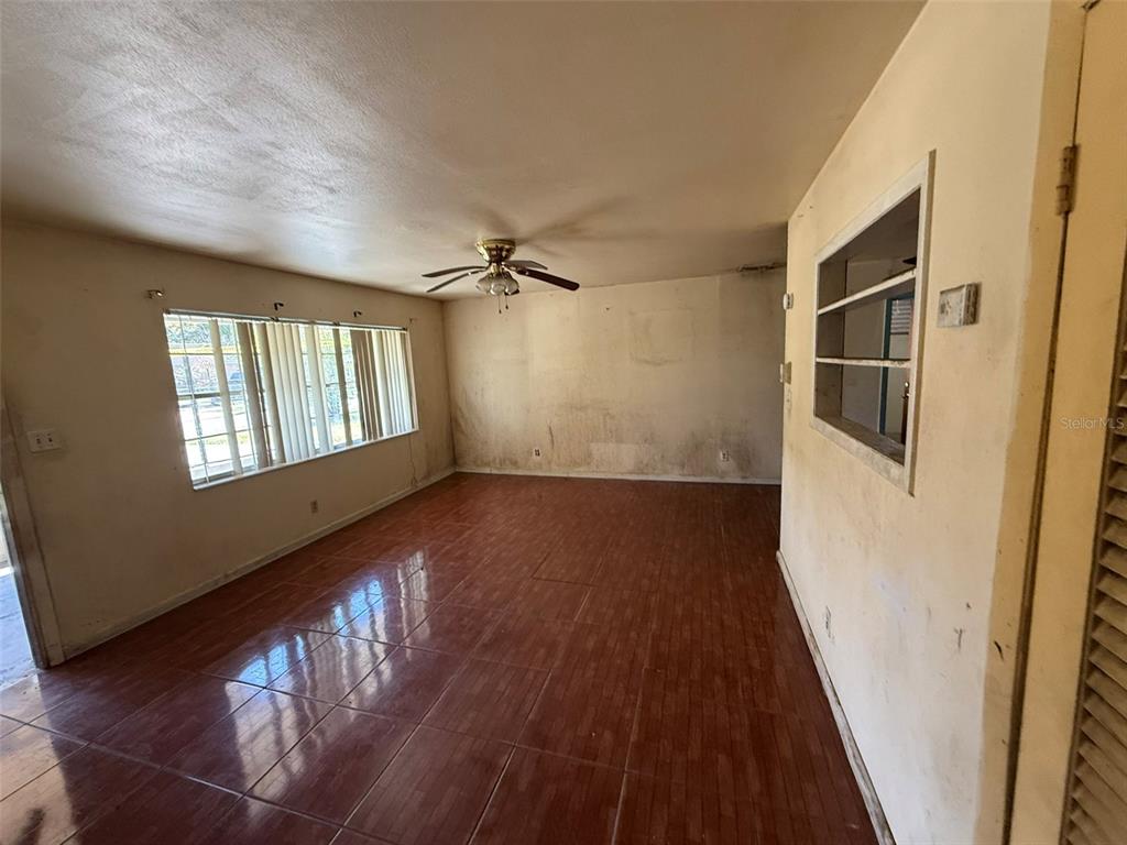 An empty room features tiled flooring, a ceiling fan, and walls with visible surface staining — 816 17TH COURT E, BRADENTON, FL