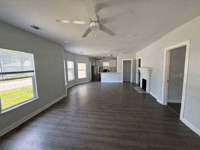 An open-concept living area features gray wood-look flooring, a ceiling fan, and a brick fireplace — 295 S OAK AVENUE, BARTOW, FL