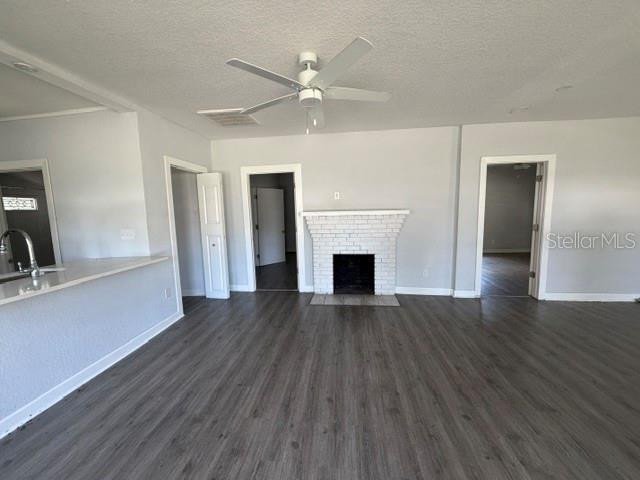 A living room features gray wood-look flooring, a white brick fireplace, and a ceiling fan — 295 S OAK AVENUE, BARTOW, FL