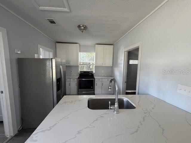 A kitchen features white cabinets, a stainless steel refrigerator, a black stove, and a quartz island — 295 S OAK AVENUE, BARTOW, FL