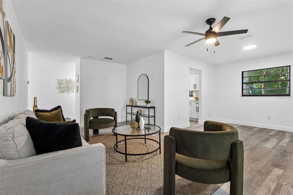 A living room features a grey sofa, two olive chairs, a coffee table, and wood flooring — 536 BISON CIRCLE, APOPKA, FL