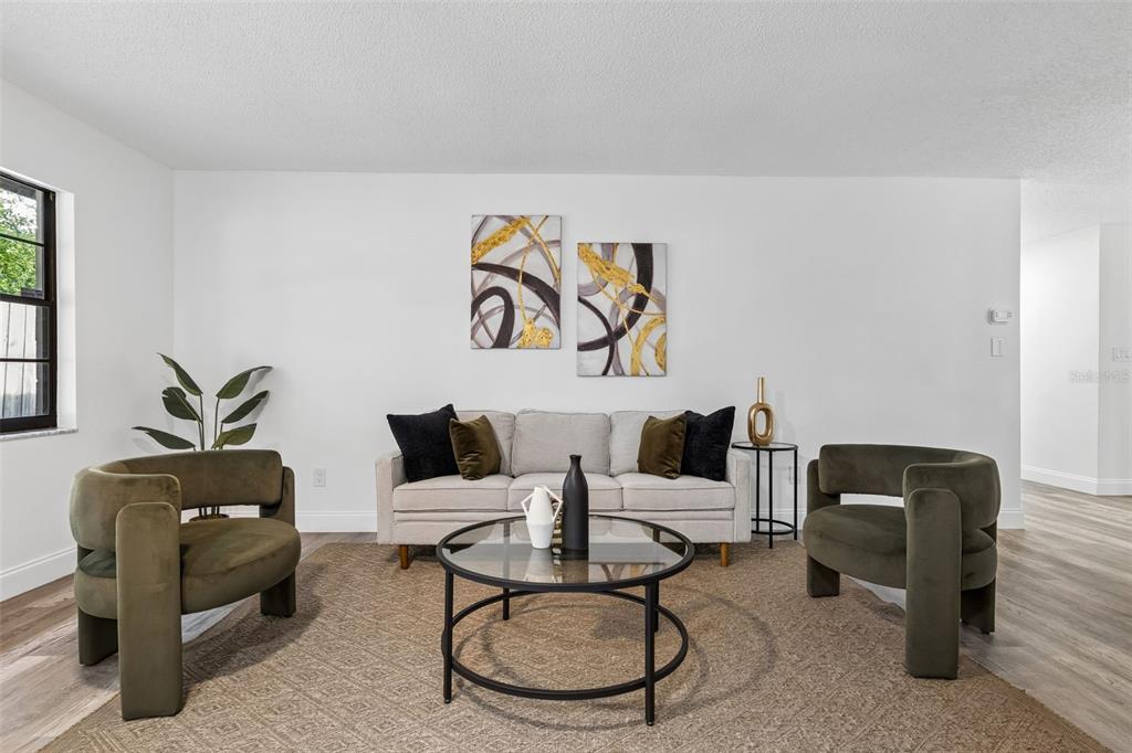 A living room features a light sofa, two olive armchairs, a glass coffee table, and artwork — 536 BISON CIRCLE, APOPKA, FL