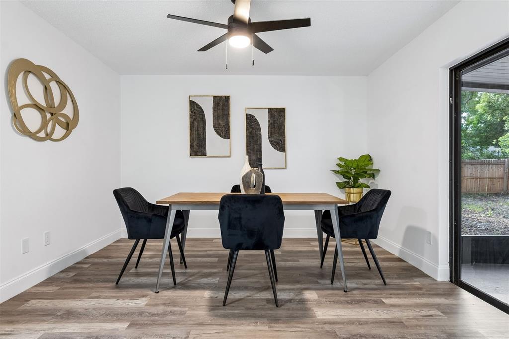 A dining room features a wooden table, black velvet chairs, wall art, and wood-look flooring — 536 BISON CIRCLE, APOPKA, FL