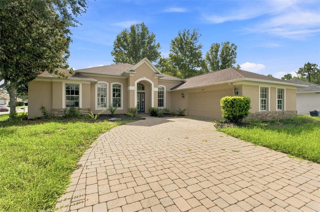 A single-story tan stucco house with a paver driveway and a two-car garage — 5598 THORNGROVE WAY, SPRING HILL, FL