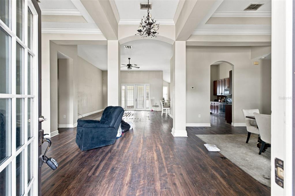 A view from an open doorway into a living area with dark wood-look flooring — 5598 THORNGROVE WAY, SPRING HILL, FL