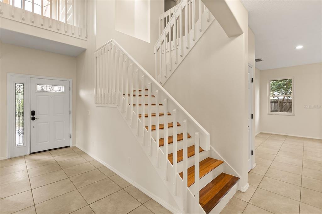 An entryway features a white staircase with wood treads, tile flooring, and a front door — 425 CARRIAGE WAY COURT, OVIEDO, FL