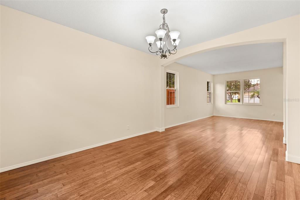 An empty room with hardwood floors, a chandelier, and an arched entryway to another space — 425 CARRIAGE WAY COURT, OVIEDO, FL