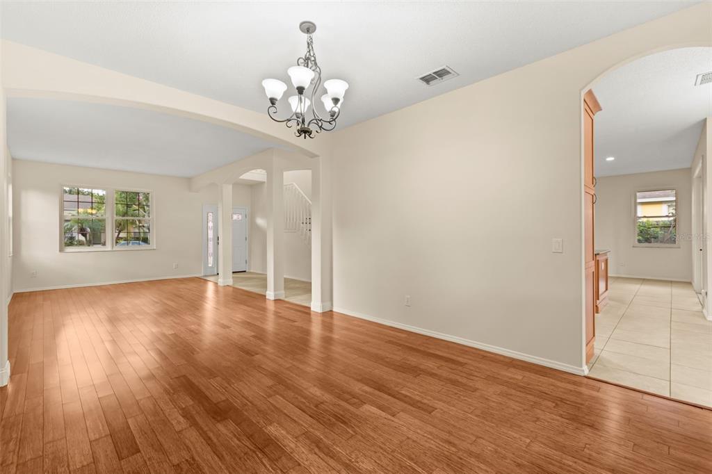 A dining room with hardwood floors, a chandelier, and an arched entryway to the kitchen — 425 CARRIAGE WAY COURT, OVIEDO, FL
