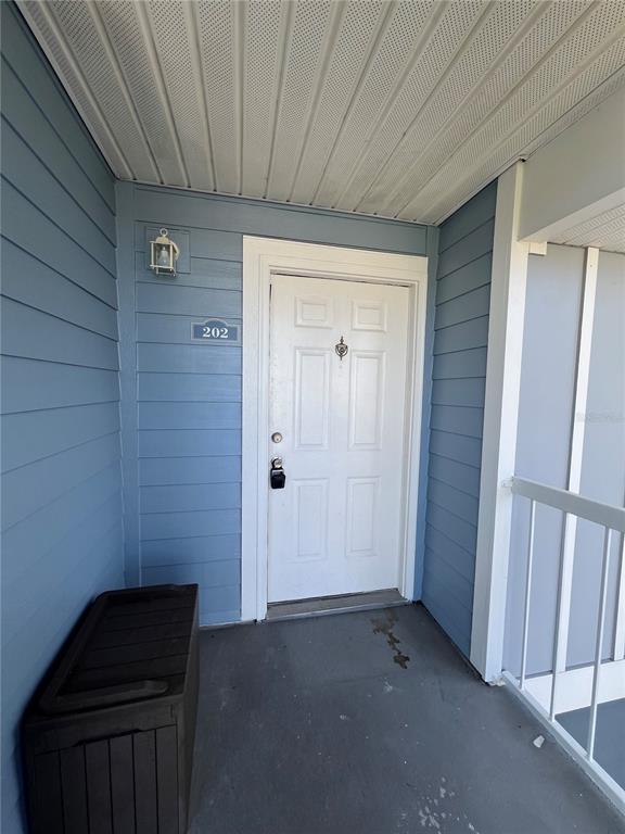 A two-story apartment building features light blue siding, white trim, and an exterior staircase — 718 SUGAR BAY WAY UNIT 202, LAKE MARY, FL