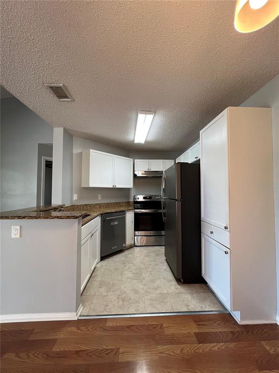 An open-concept living area with wood flooring, a kitchen island, and a sliding glass door — 718 SUGAR BAY WAY UNIT 202, LAKE MARY, FL