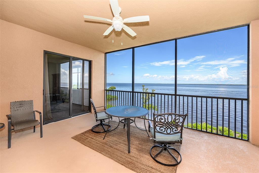 A screened-in balcony features a dining set, a separate chair, and a waterfront view — 85 VIVANTE BOULEVARD UNIT 8542, PUNTA GORDA, FL