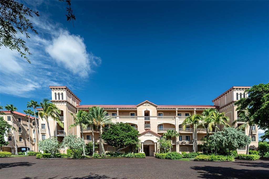 A multi-story tan stucco building with a red roof and palm trees under blue sky — 85 VIVANTE BOULEVARD UNIT 8542, PUNTA GORDA, FL