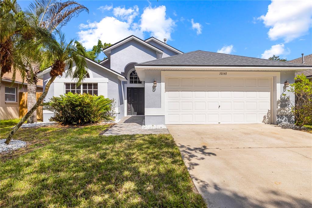 A single-story house with a light blue exterior, a two-car garage, and a palm tree — 10148 SOMERSBY DRIVE, RIVERVIEW, FL