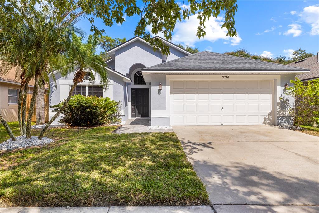 A single-story house with a light blue exterior, a two-car garage, and a palm tree — 10148 SOMERSBY DRIVE, RIVERVIEW, FL