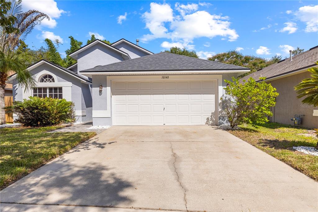 A single-story house with a white garage door, gray stucco siding, and a concrete driveway — 10148 SOMERSBY DRIVE, RIVERVIEW, FL