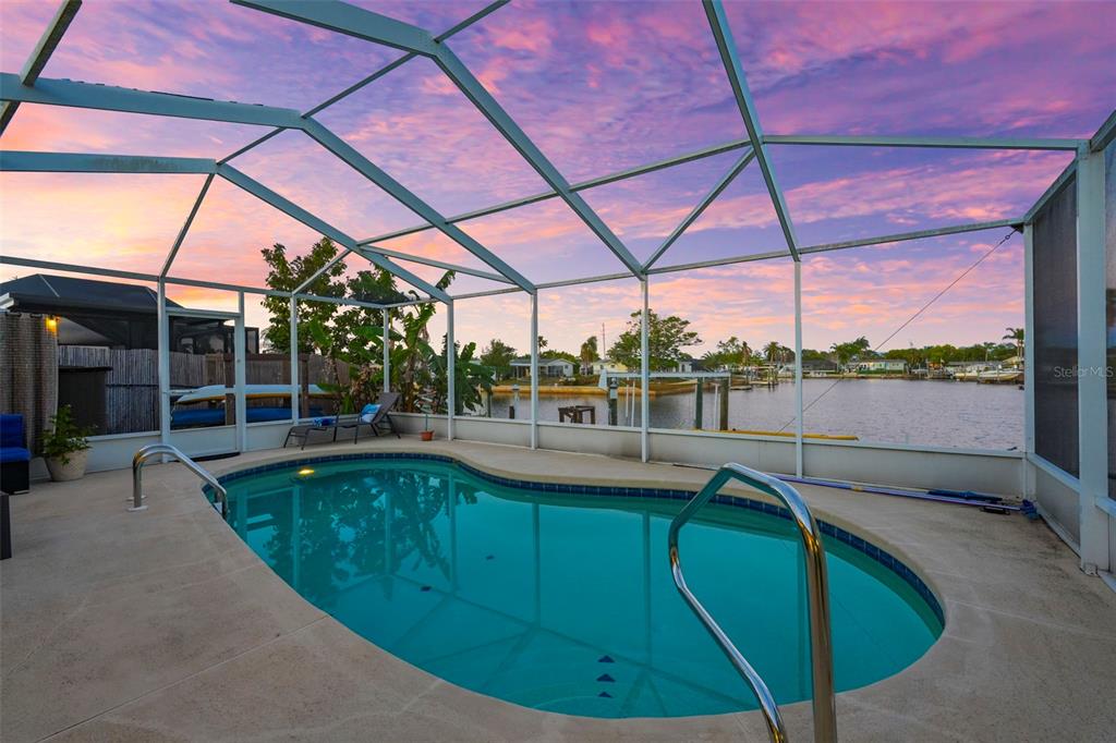A single-story light green house with a palm tree in the front yard at sunset — 12532 5TH ISLE, HUDSON, FL