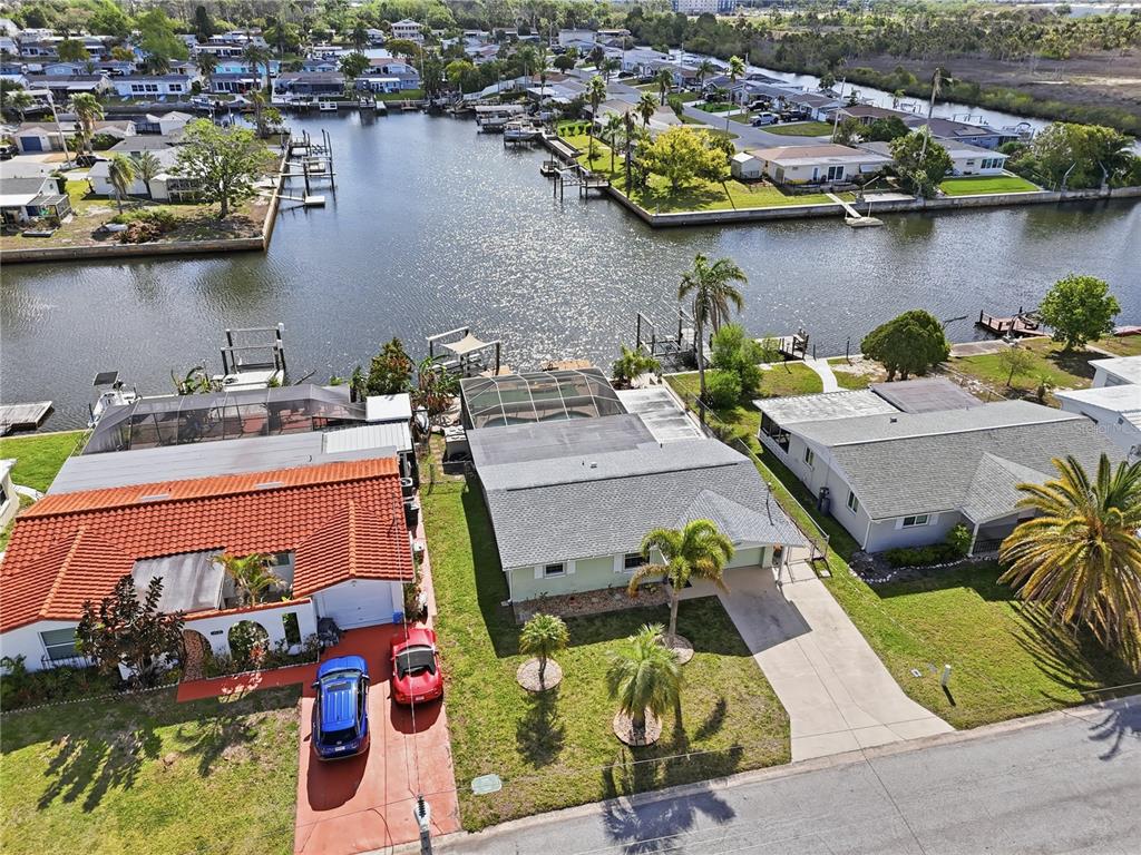 An aerial view shows three waterfront houses with boat docks along a canal — 12532 5TH ISLE, HUDSON, FL