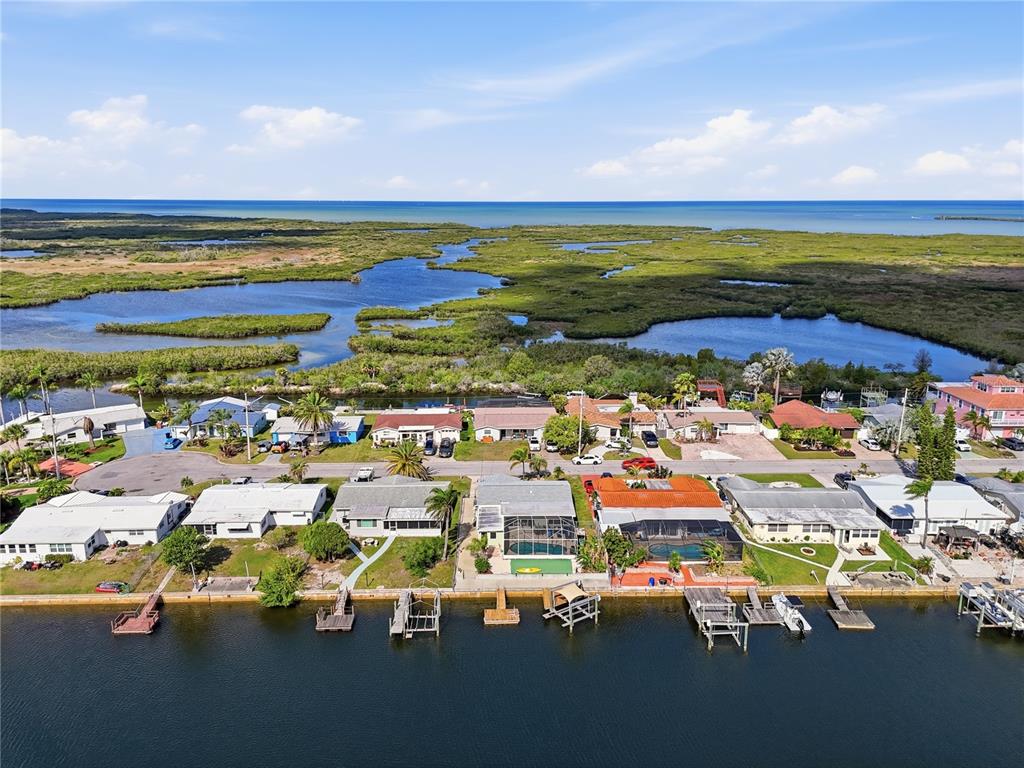 An aerial view shows waterfront houses with private docks along a canal near wetlands — 12532 5TH ISLE, HUDSON, FL