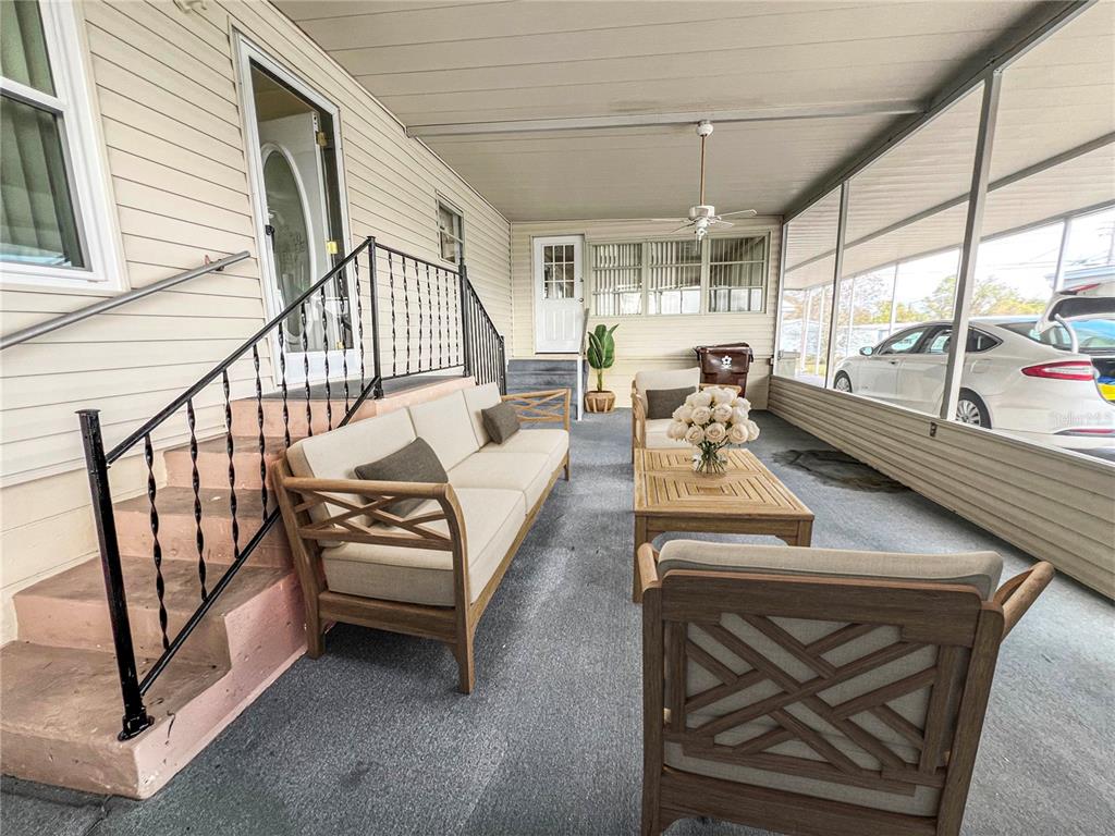 A screened-in porch features light-colored patio furniture, a wooden coffee table, and concrete stairs — 326 MARTIN DRIVE, LAKELAND, FL