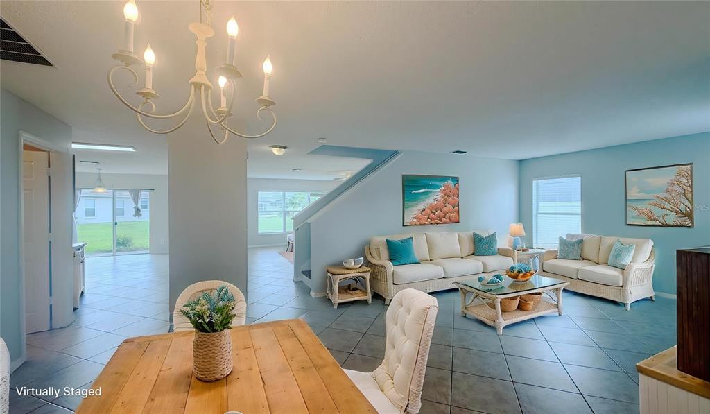 A living and dining area with light blue walls, tile flooring, and wicker furniture — 831 HORSESHOE FALLS DRIVE, ORLANDO, FL