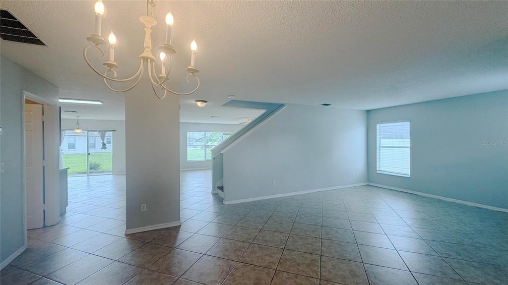 An open-concept living area features light blue walls, tile flooring, and a white chandelier — 831 HORSESHOE FALLS DRIVE, ORLANDO, FL