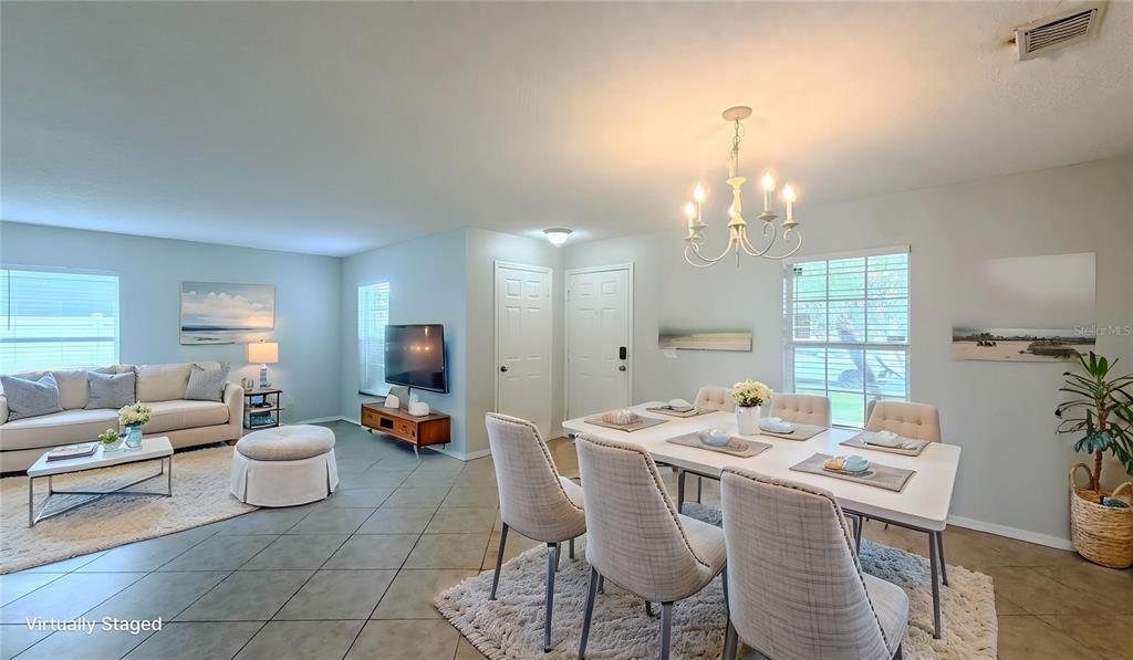 An open-concept living and dining area features tile flooring, a chandelier, and neutral furnishings — 831 HORSESHOE FALLS DRIVE, ORLANDO, FL