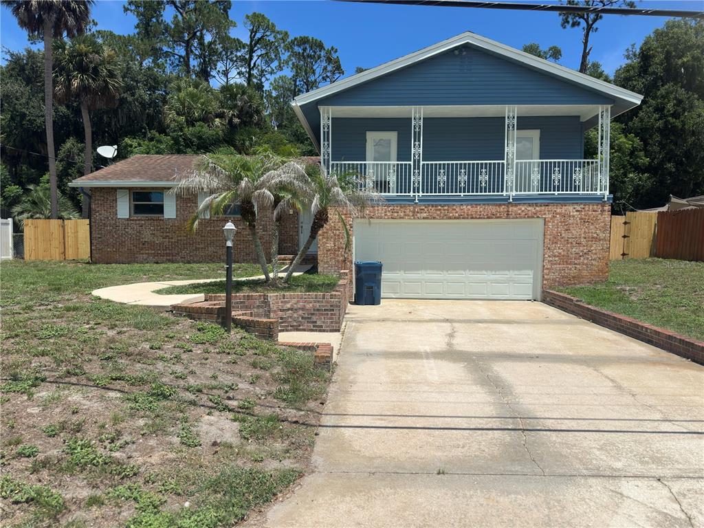 A two-story house with a brick lower level, blue siding, and a white garage door — 172 SEMINOLE DRIVE, ORMOND BEACH, FL