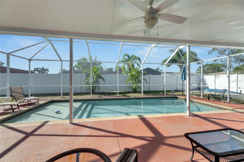A covered patio overlooks a swimming pool enclosed by a screen cage in a backyard — 412 FLAMINGO DRIVE, APOLLO BEACH, FL