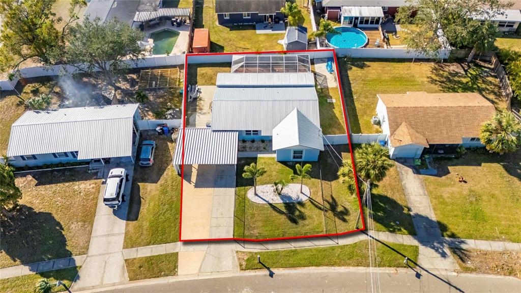 An aerial view shows a single-story house with a metal roof and a fenced yard — 412 FLAMINGO DRIVE, APOLLO BEACH, FL