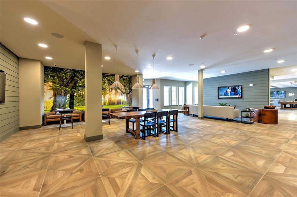 A spacious community room features wood-look tile flooring, a large dining table, and wall murals — 6629 DAN DICIOLLA DRIVE UNIT B2, WILDWOOD, FL