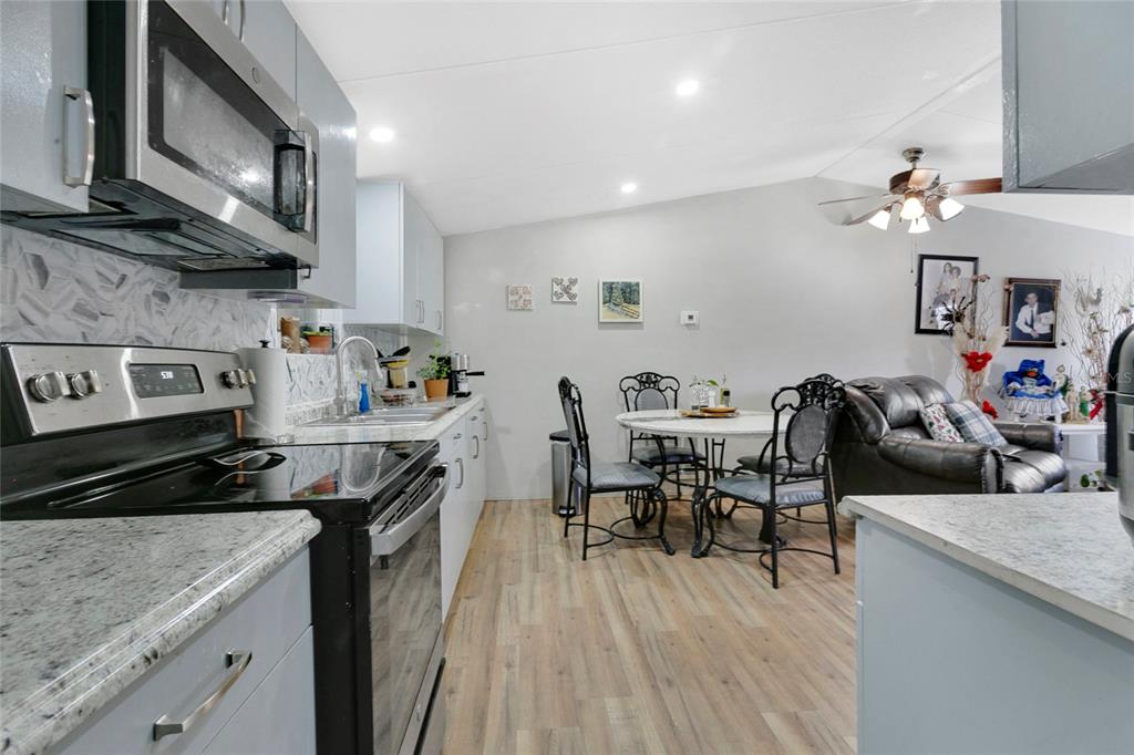 A kitchen with light blue cabinets, granite countertops, and a dining area in an open layout — 12531 NE 18TH STREET, WILLISTON, FL