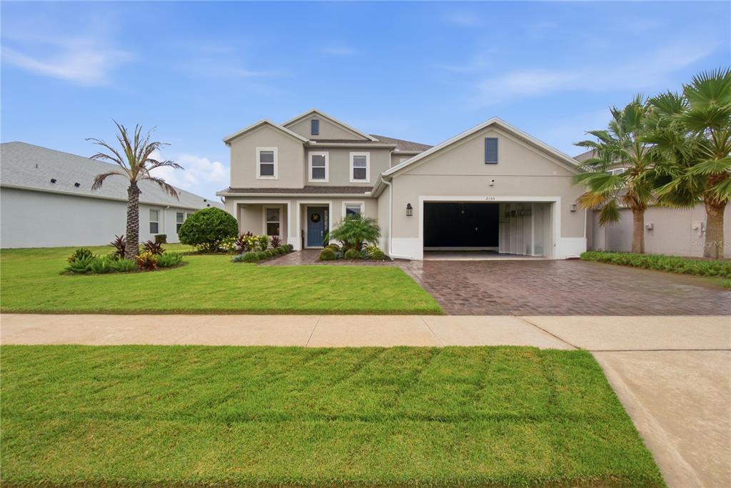 A two-story suburban house with a beige exterior, a two-car garage, and a paved driveway — 2155 TIMBER CREEK LANE, CLERMONT, FL
